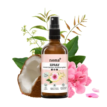 Eine Sprühflasche mit der Aufschrift "noms+ ZPRAY" mit einem Anti-Zecken-Komplex, umgeben von Kokosnuss- und Blütendekoren, die vegane Haustierpflege fördert.