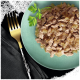 Nourriture pour animaux sur une assiette vert clair avec de la viande effilochée dans une sauce, garnie de persil, à côté d'une fourchette dorée sur un tissu sombre.