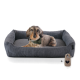 Ein gemütliches graues Hundebett mit einem Dackel, der ein grünes Halstuch trägt und bequem darin ruht, begleitet von einem herzförmigen Anhänger.