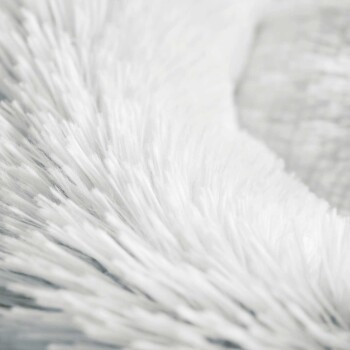 Nahaufnahme eines weichen, flauschigen weißen Haustierbettes, das seine plüschige Textur und einladende Erscheinung zeigt.