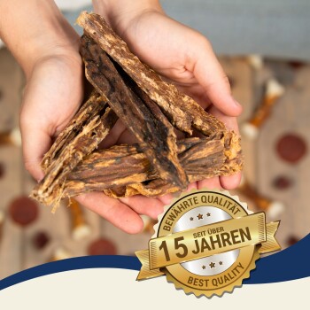 Eine Person hält ein Bündel natürlicher Haustierleckerlis, mit einem goldenen Abzeichen, das "Bewährte Qualität seit über 15 Jahren" und "Beste Qualität" besagt.