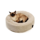 Siamkatze mit Point-Zeichnung (dunkles Gesicht und Ohren) zusammengerollt in einem beigen Cord-Donut-Katzenbett; kleines schwarzes Etikett mit weißem Text.