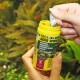 Eine Person hält einen gelben Behälter mit JBL Pro Novo Spirulina Fischfutter, das für Herbivoren gekennzeichnet ist, mit Flocken für Fische von 8-20 cm.