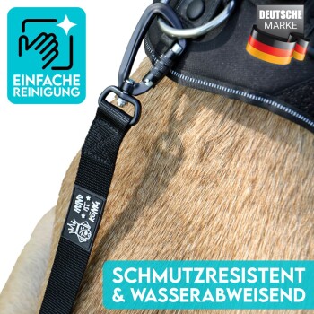 Nahaufnahme eines Hundegeschirrs mit einem schwarzen Riemen und einem Metallclip auf Fell, mit dem Text: "EINFACHE REINIGUNG" und "SCHMUTZRESISTENT."