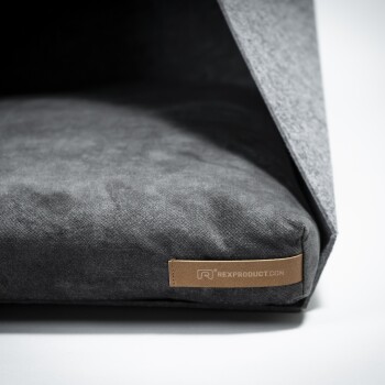 Graues Haustierbett mit einem weichen Kissen und einem gefalteten Bezug, mit einem Lederschild, auf dem "REXPRODUCT.COM" steht.