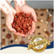 Hände halten einen Stapel kleiner, roter Hundeleckerlis mit einem goldenen Abzeichen, das in der Ecke "Best Quality seit über 15 Jahren" besagt.