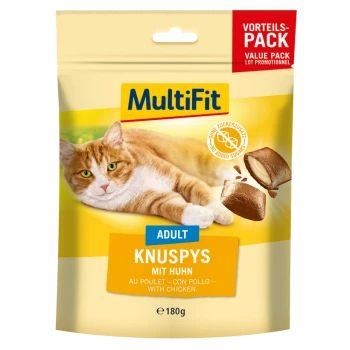 Un chat se prélasse près d'un sac de friandises pour chats MultiFit étiqueté "Knuspy mit Huhn" avec une bannière de pack de valeur et le symbole "Sans sucres ajoutés."