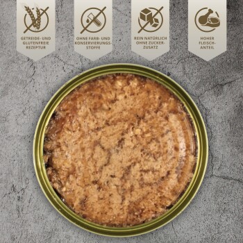 Eine weiße Schüssel, gefüllt mit einer strukturierten, braunen Tiernahrung, beschriftet "PREMIUM" in einem goldenen Banner, auf einer Holzoberfläche mit grünem Gras im Hintergrund.