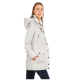 Eine Frau, die eine hellgraue, kapuzenjacke mit mehreren Taschen trägt, seitlich vor einem weißen Hintergrund stehend.