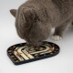 Eine graue Katze leckt eine Puzzle-Futtermatte, die mit cremigem Futter und trockenem Futter gefüllt ist, um die Haustiere während der Fütterung zu beschäftigen.