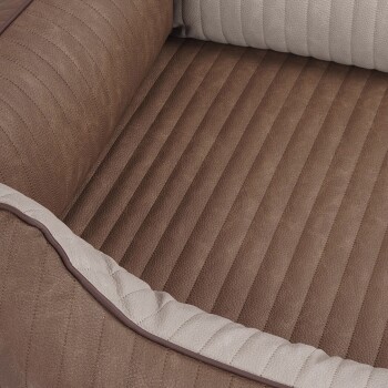 Eine Nahaufnahme eines Haustierbettes mit einer braunen, strukturierten Basis mit vertikalen Streifen und einem hellen, gesteppten Rand.