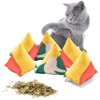 Eine verspielte graue Katze interagiert mit bunten, mit Katzenminze gefüllten Pyramidentoys in Gelb und Rot, mit getrockneter Katzenminze, die in der Nähe verstreut ist.