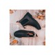Ein Paar schwarze Gummistiefel auf einem Holzboden mit verstreuten Herbstblättern.