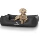 Ein hellbrauner Hund, der auf einem schwarzen, gesteppten Haustierbett liegt, auf dem das Logo 'KNUFFELWUFFF' deutlich auf der Vorderseite zu sehen ist.