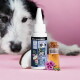 Flasche des Haustierprodukts 'Z-Spot für Hunde' auf einem rosa Hintergrund, begleitet von einem kleinen Glasfläschchen mit Öl, einer Kokosnuss-Scheibe und Blumen.