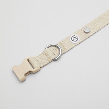 Beige Hundehalsband mit einer Kunststoffschnalle und einem Metall-D-Ring, mit einem Anhänger, der 'Nachhaltiger Haustierstil' liest.