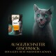Eine graue Katze leckt sich die Lippen neben einem Sheba Sauce Collection Beutel mit der Aufschrift "sauce lover mit Truthahn" und verlockendem deutschen Text.