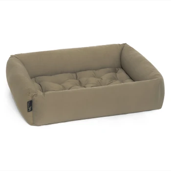 Ein plüschiges, rechteckiges Haustierbett in einem sanften Beigeton mit gepolstertem Bezug und erhöhten Seiten, mit einem kleinen schwarzen Etikett an der Seite.