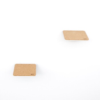 Zwei kleine, quadratische Korkuntersetzer mit weißen Rändern, vor einem schlichten weißen Hintergrund platziert.