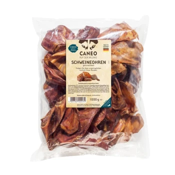 Un sac en plastique transparent rempli d'oreilles de porc séchées pour chiens, étiqueté "Caneo Schweineohren" avec un poids de 1000g, fabriqué en Allemagne.