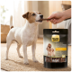 Jack Russell prenant une friandise tressée d'une main à côté d'une pochette de bâtonnets pour adultes Select Gold Sensitive