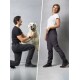 Ein Mann kniet neben einem glücklichen Golden Retriever, während eine Frau selbstbewusst in stylischen schwarzen Hosen steht und tierfreundliche Kleidung präsentiert.