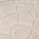 Gros plan d'un lit pour animaux doux, de couleur crème, avec une surface texturée en peluche présentant un motif matelassé.