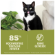 Eine schwarz-weiße Katze leckt sich die Lippen, steht neben einer grünen Pflanze. Text lautet '85% HOCHWERTIGE TIERISCHE ZUTATEN' und 'OHNE GETREIDE.'