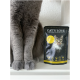 Graue Katzenpfoten neben einem Paket 'Cat's Love' Katzenfutter, mit einem Katzenbild und Text, der Zutaten wie Rindfleisch und Truthahn hervorhebt.