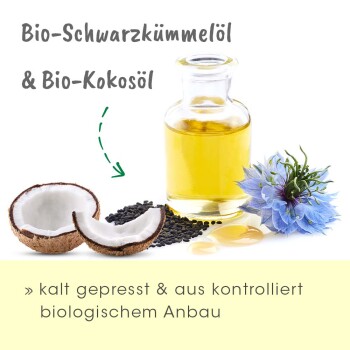 Bio Schwarzkümmelöl und Bio Kokosöl in einer Glasflasche, mit Kokosnüssen, schwarzen Samen und einer blauen Blume; kaltgepresst und biologisch.