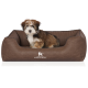 Ein kleiner, flauschiger Hund sitzt bequem in einem braunen Hundebett mit strukturiertem Innenraum, mit dem Logo "KNUFFELWUFF."