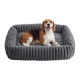 Beagle lächelt und liegt in einem grauen, gerippten, plüschigen rechteckigen Hundebett mit erhöhten Seitenwänden, weißer Hintergrund.