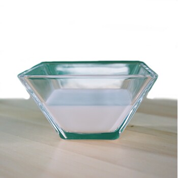 Eine klare Glasschüssel, gefüllt mit einer hellrosa Flüssigkeit, auf einer Holzoberfläche platziert.