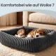 Beagle-Welpe schläft in einem grauen, plüschigen Cord-Haustierbett auf einem Teppich neben dem Sofa; darüber steht der Text 'Komfortabel wie auf Wolke 7'.