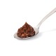 A silver spoon holds a dollop of rich, brown pet food paste, showcasing its smooth, creamy texture against a white background.