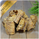 Ein Haufen hochwertiger Haustierleckereien, die gerollten, getrockneten Fleischsnacks ähneln, auf einer Holzoberfläche mit grünem Gras im Hintergrund präsentiert.