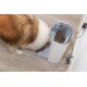 Ein Hund mit einem flauschigen Fell frisst aus einem modernen automatischen Haustierfutterspender, der mit Kibble gefüllt ist, auf einem Holzboden.