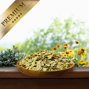 Eine Holzschüssel mit grünen Tierfutterflocken auf einer Holzoberfläche, mit lebhaften Blumen im Hintergrund und einem goldenen "PREMIUM"-Label in der Ecke.