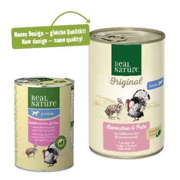 Zwei Dosen Haustierfutter von Real Nature: eine grüne Dose mit der Aufschrift "Junior" und einem rosa Etikett, und eine beige Dose mit der Aufschrift "Original" mit "Kanichen & Pute."