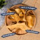 Ein Holzbrett mit Hundekauartikeln, beschriftet auf Deutsch: "zahnpflegend", "reich an Kollagen", "naturbelassen" und "Beschäftigung."