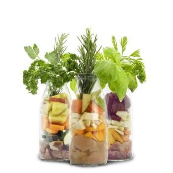 Drei Glasbehälter gefüllt mit buntem, gehacktem Gemüse, Obst und frischen Kräutern, die eine gesunde Option für Haustierfutter zeigen.