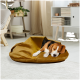 Ein gemütliches, senfgelbes Haustierbett mit einem teilweise eingerollten Beagle darin, in einem hellen, modernen Wohnzimmer mit Pflanzen und hellen Vorhängen.