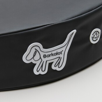 Schwarzes Hundebett mit einem weißen "Barkalot"-Logo mit einer Hundesilhouette und einem Nachhaltigkeitssymbol.