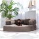 Ein gemütliches, plüschiges Hundebett in neutralem Farbton, mit einem Dackel, der bequem darauf ruht, und einer grünen Pflanze im Hintergrund.