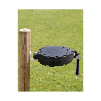 Ein schwarzer Haustierspielzeugspender, der an einem Holzpfosten montiert ist, vor einem grasbewachsenen Hintergrund.