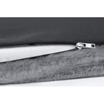 Nahaufnahme eines Haustierbettes mit einem schwarzen Reißverschlussoberteil, das ein gepunktetes Muster und eine weiche graue Fellunterlage hat.