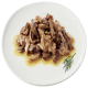 Ein Teller mit fein gehacktem, feuchtem Fleisch in einer herzhaften Sauce, garniert mit einem Zweig Dill.