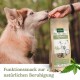 Eine Nahaufnahme eines Hundes, der eine Hand schnüffelt, die ein Leckerli anbietet. Die Leckerli-Verpackung, beschriftet mit "Hanfkekse - Hanfleckerlis", fördert die natürliche Beruhigung für Haustiere.