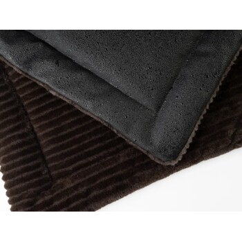 Eine Nahaufnahme eines Haustierbettes mit einem strukturierten braunen Stoff und einer glatten schwarzen wasserdichten Schicht oben, die sein doppelseitiges Design zeigt.