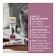 A gray cat is seen in the background next to a tube and box of GimCat Malt-Soft Paste Extra, which supports hairball elimination.
